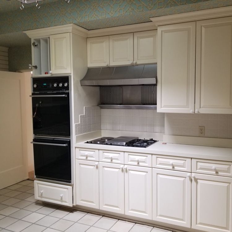 A kitchen with white cabinets and black appliances