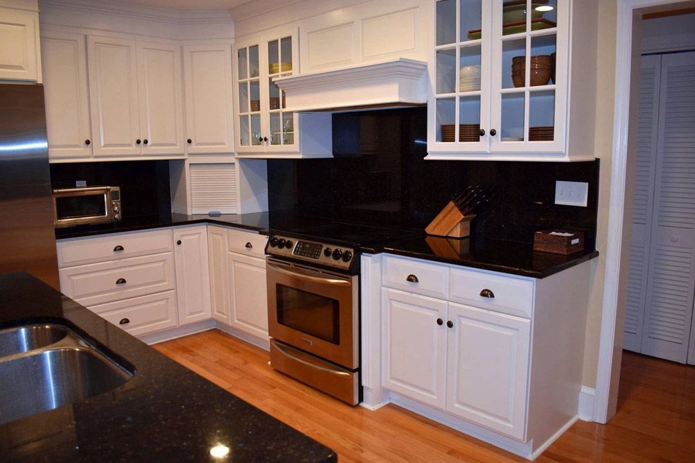 A kitchen with white cabinets and black counter tops