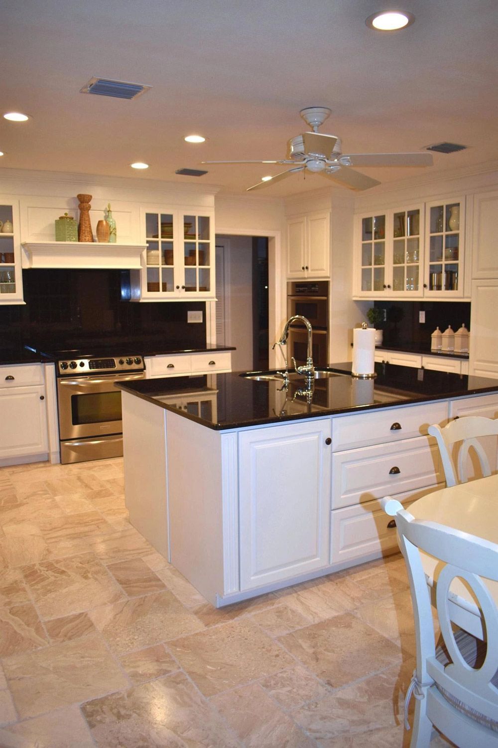 A kitchen with white cabinets and black counter tops