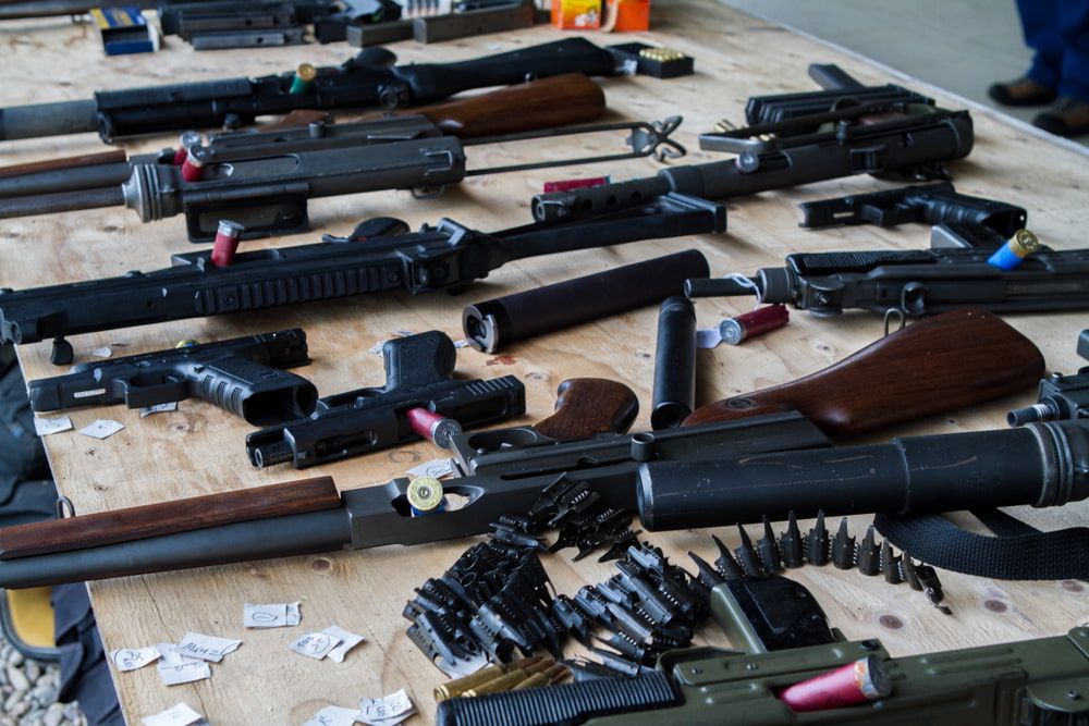 A Variety of Firearms and Ammunition Are Displayed on a Wooden Table — Mackay Shooters Supplies in Emerald, QLD
