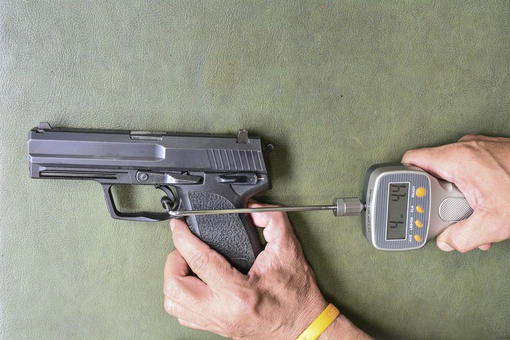 A Person Holds a Black Handgun While Measuring the Trigger Pull — Mackay Shooters Supplies in Paget, QLD