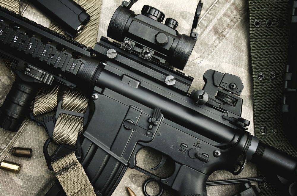 Close-up of a Tactical Rifle on a Textured Fabric Surface, Featuring a Mounted Scope and Tan Strap — Mackay Shooters Supplies in Proserpine, QLD