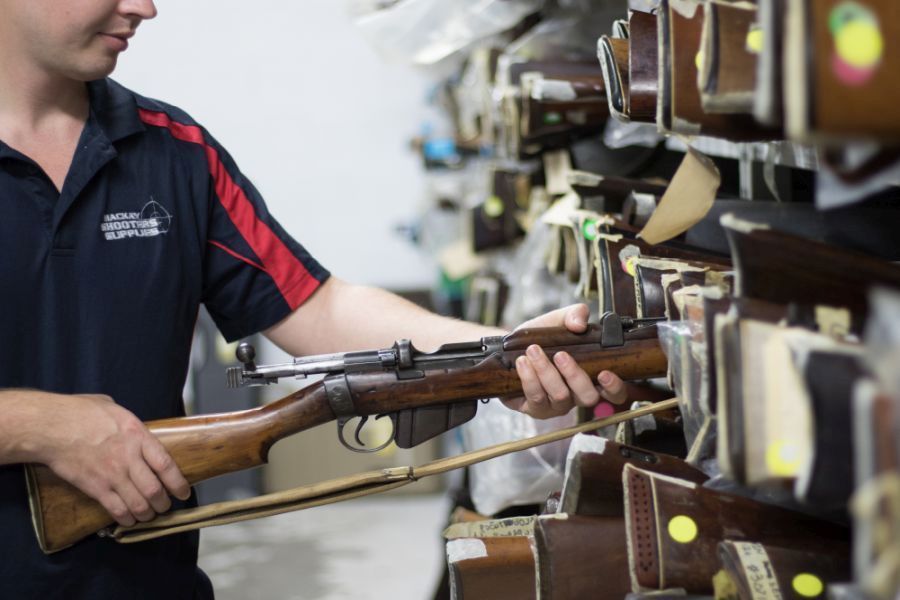 A Black Rifle With a Mounted Scope is Displayed on a Red Rack in a Gun Shop — Mackay Shooters Supplies in Paget, QLD