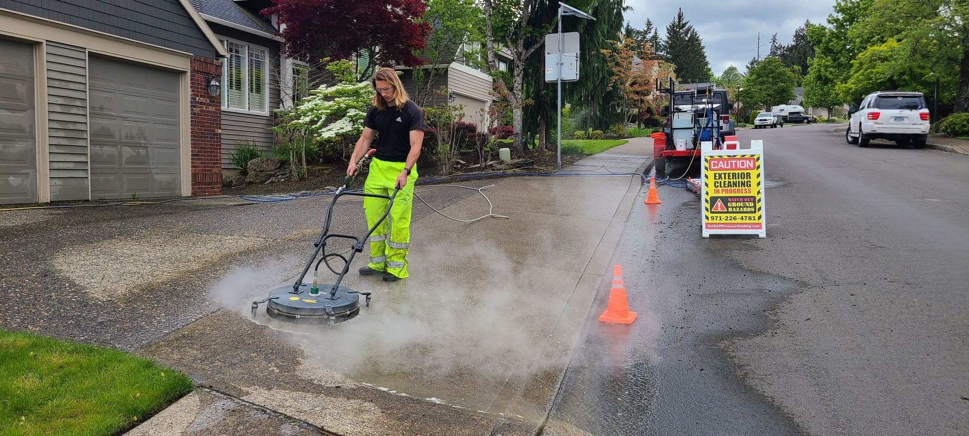 High-pressure hot water cleaning a concrete driveway, removing dirt and grime in Tigard Oregon