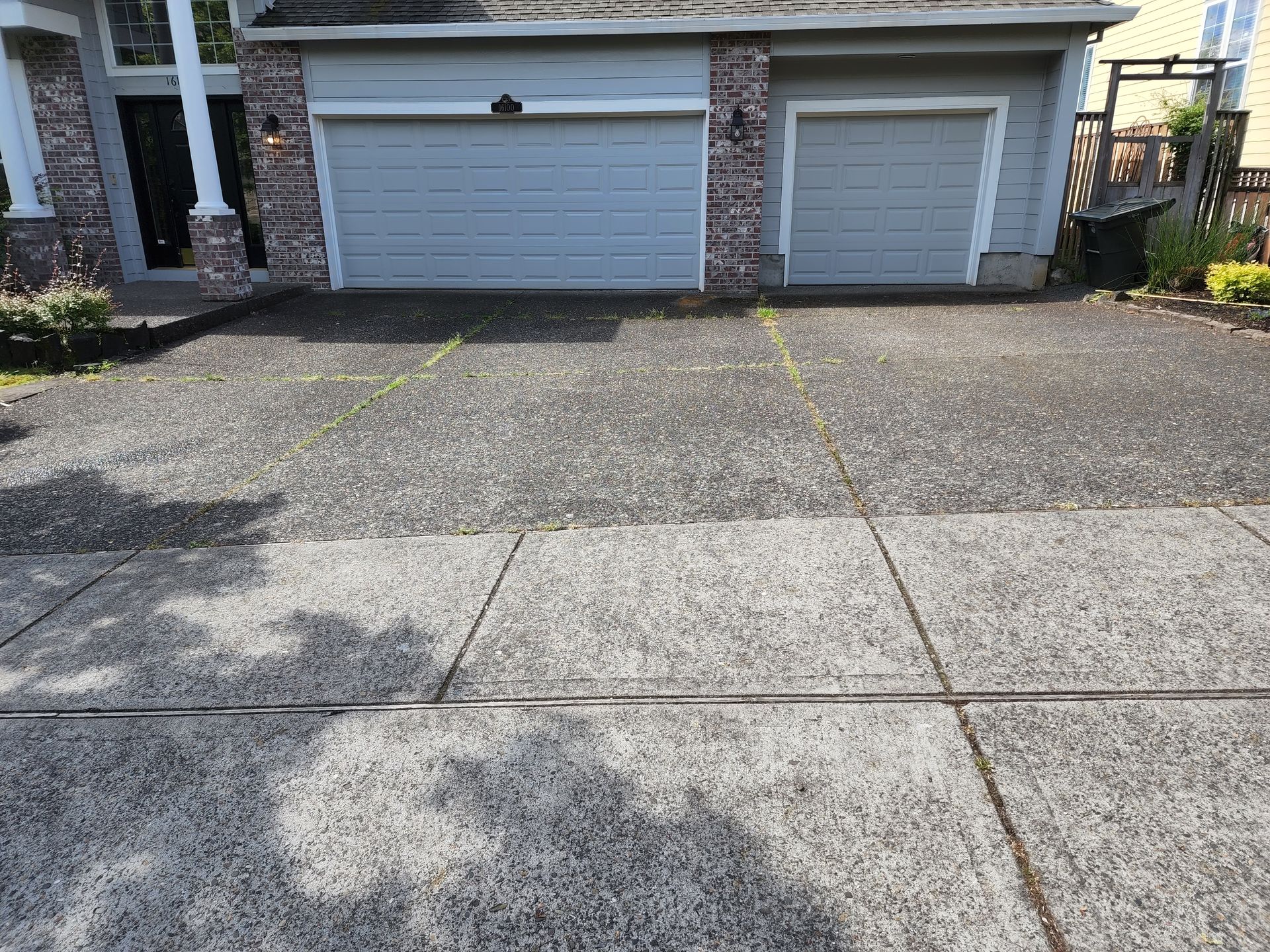 Hot water pressure washing removing mold from a home's Concrete in Tigard Oregon