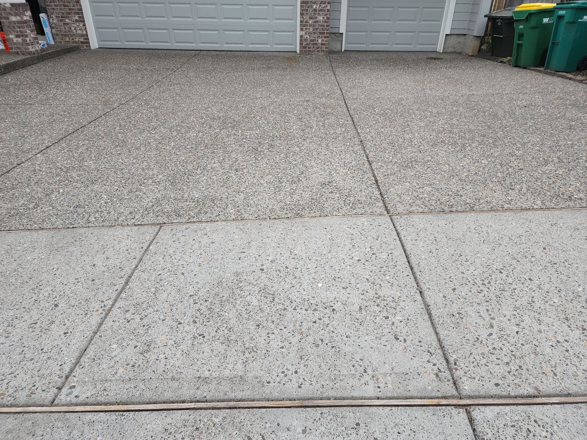 Hot water pressure washing removing mold from a home's Concrete in Tigard Oregon