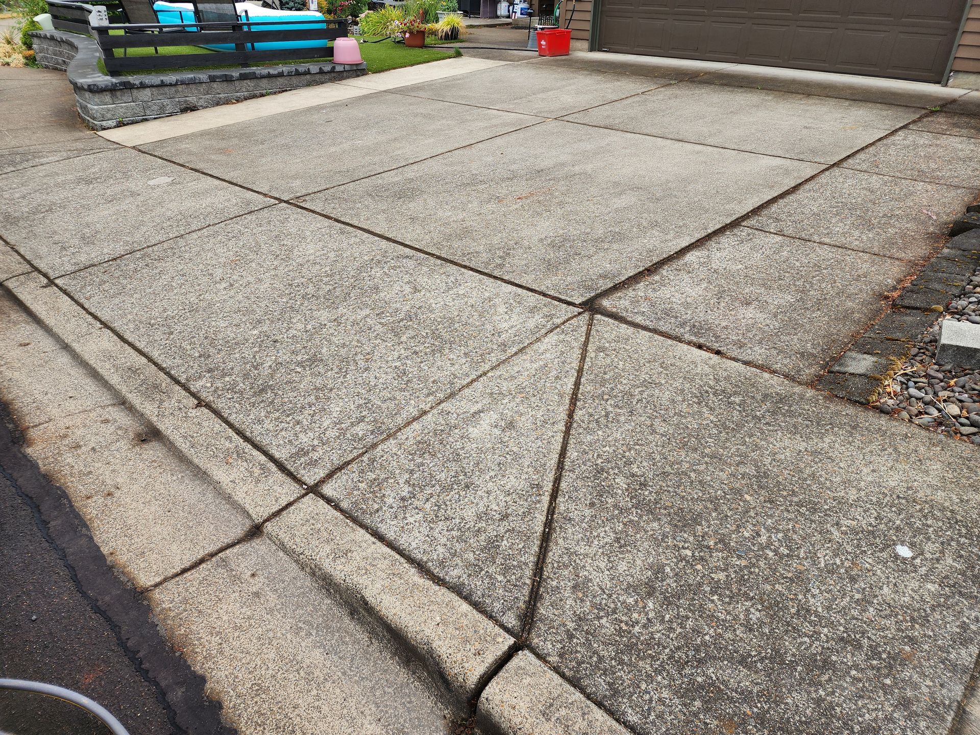 Hot water pressure washing removing mold from a home's Concrete in Tigard Oregon