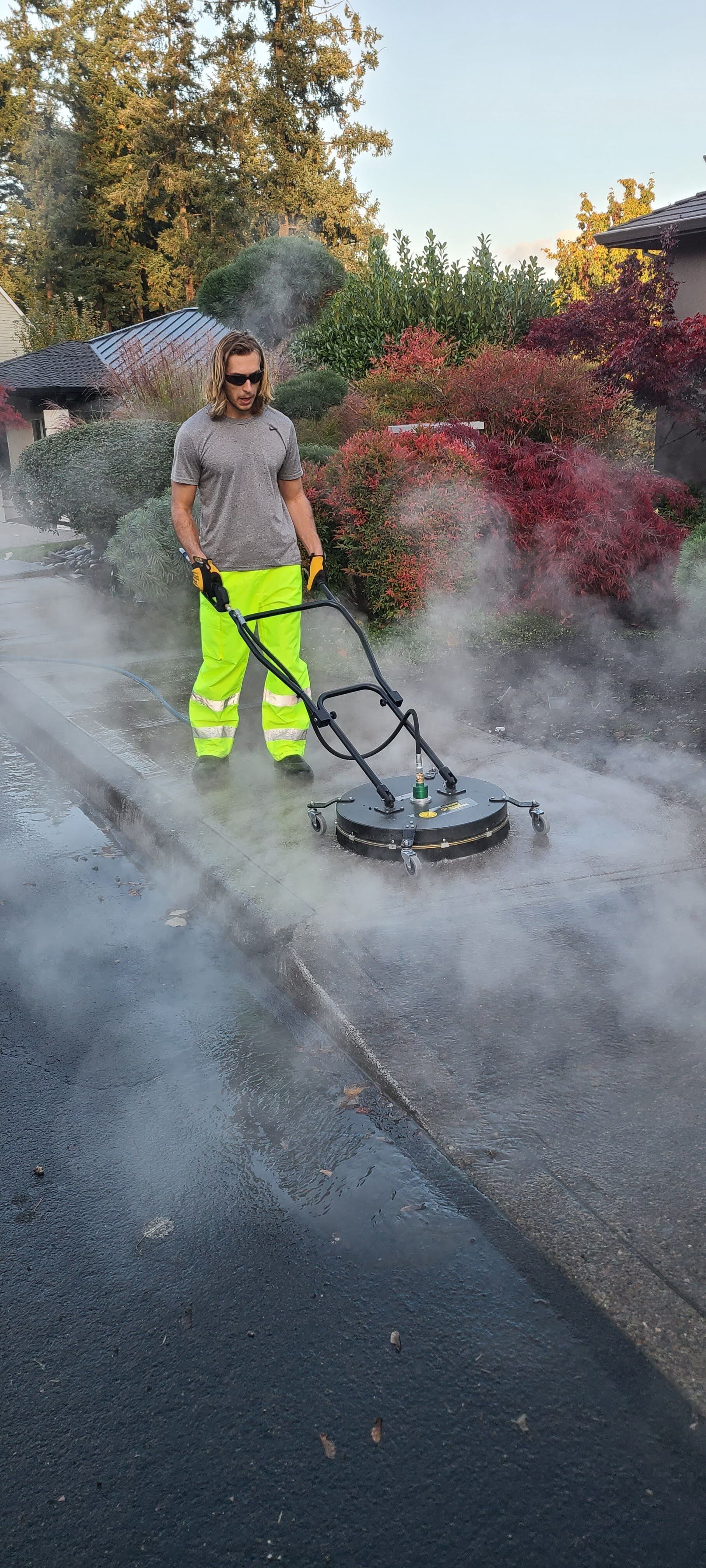 High-pressure hot water cleaning a concrete driveway, removing dirt and grime in Tigard Oregon