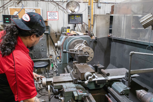 Worker in red jacket operating a metal lathe in an industrial workshop