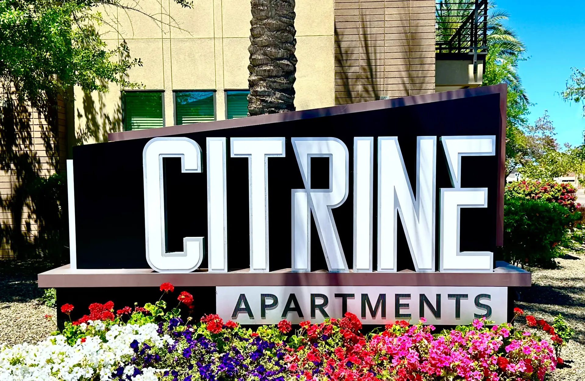 A sign for citrine apartments is surrounded by flowers