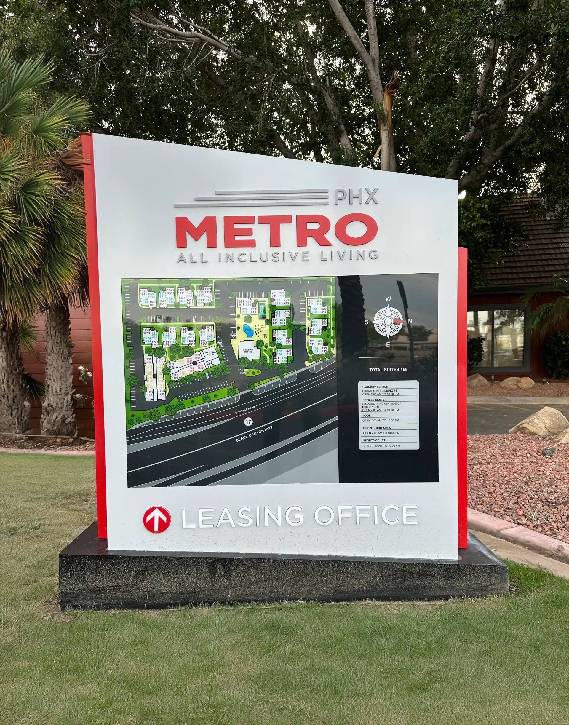 A metro sign is sitting in the grass in front of a building.