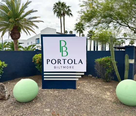 A sign for portola sits in front of a blue wall