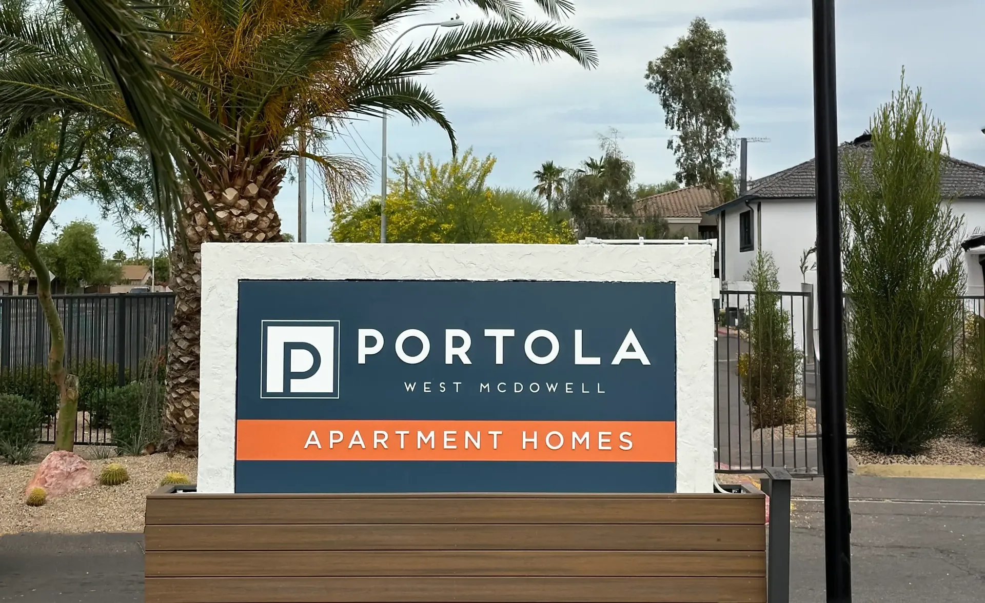 A sign for portola apartment homes is in front of a palm tree