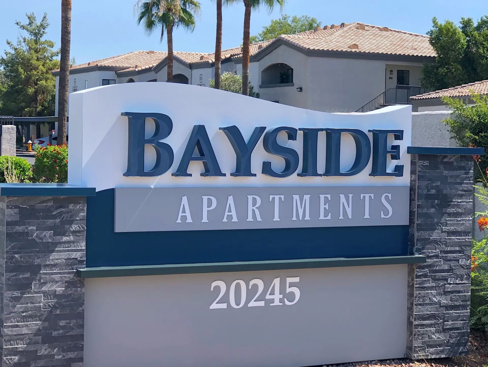 A sign for bayside apartments with a building in the background