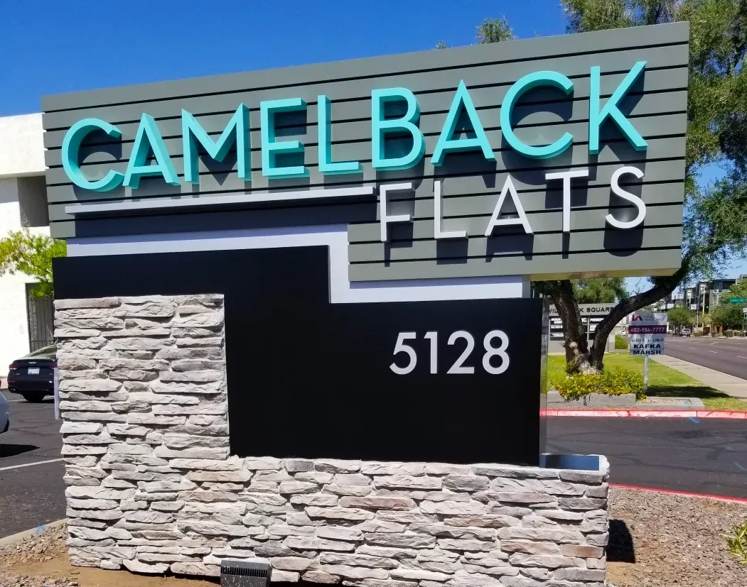 A sign for camelback flats sits on a stone wall