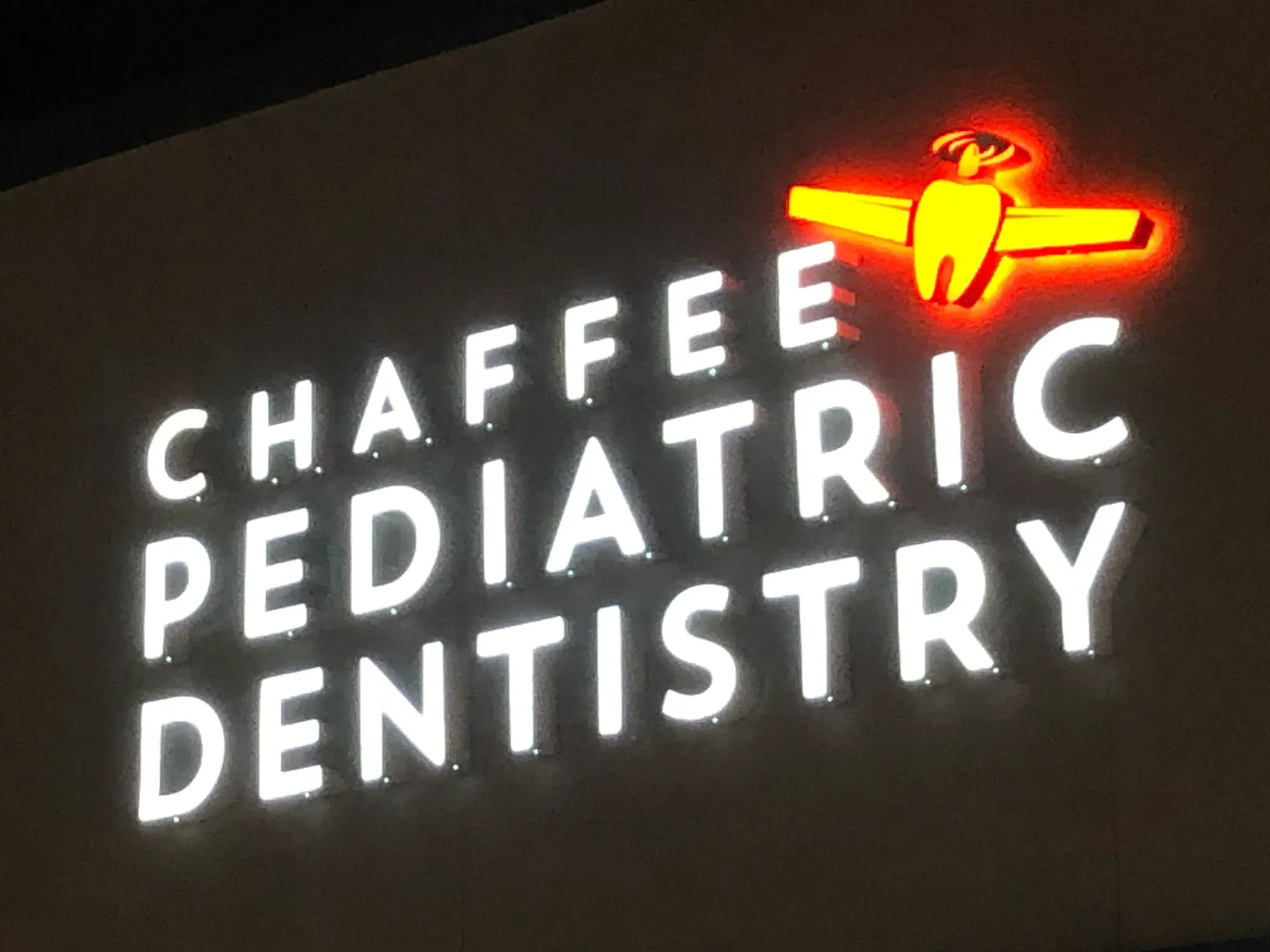 A sign for chaffee pediatric dentistry is lit up at night