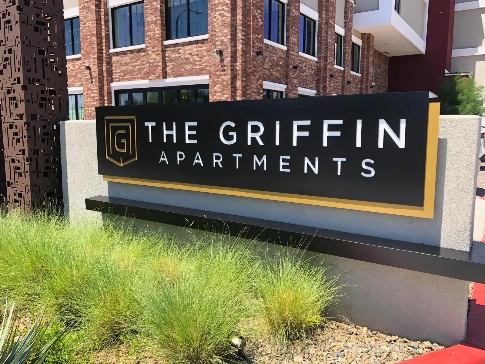 A sign for the griffin apartments is in front of a brick building