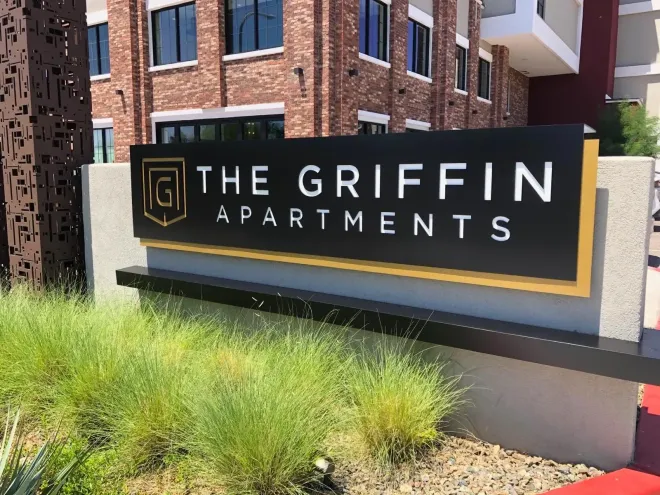 A sign for the griffin apartments is in front of a brick building