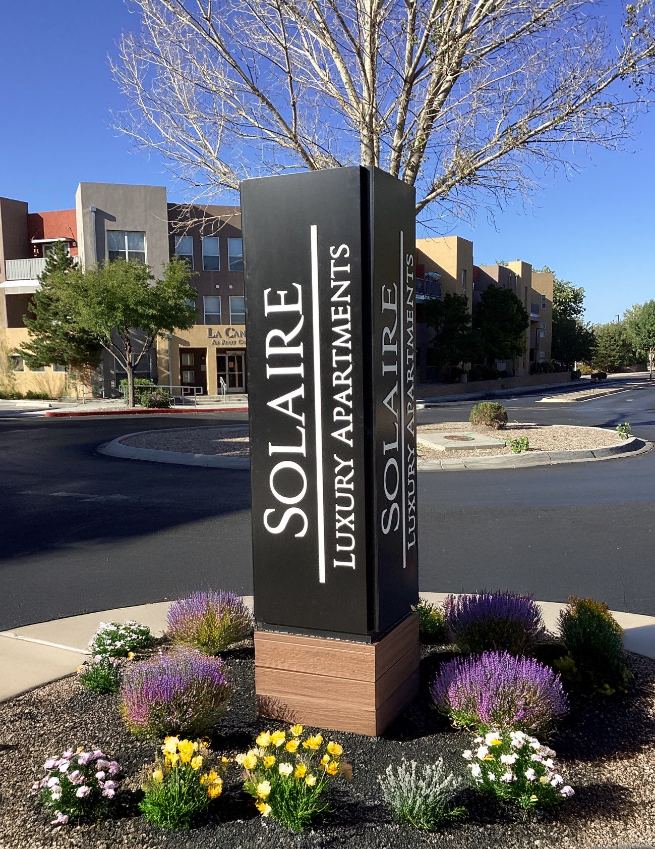 A sign for solaire luxury apartments is surrounded by flowers