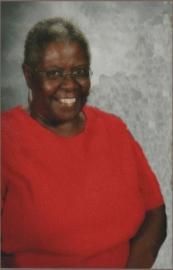 Smiling person in a red shirt posing against a gray studio backdrop