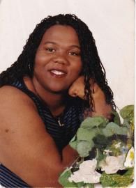 Smiling person with long dark hair posing beside a bouquet of white flowers.