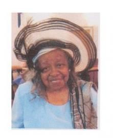 Woman smiling in a large striped hat and light blue shirt.