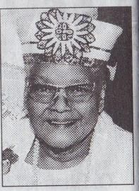 Black-and-white portrait of a smiling man wearing glasses and a decorative floral headdress.