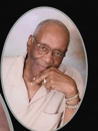 Portrait of a smiling person wearing glasses, resting their chin on a hand, in a light shirt against a dark background