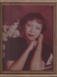 Framed portrait of a woman resting her chin on her hand against a floral background