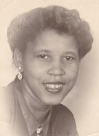 Black-and-white portrait of a smiling woman in earrings and a collared blouse.