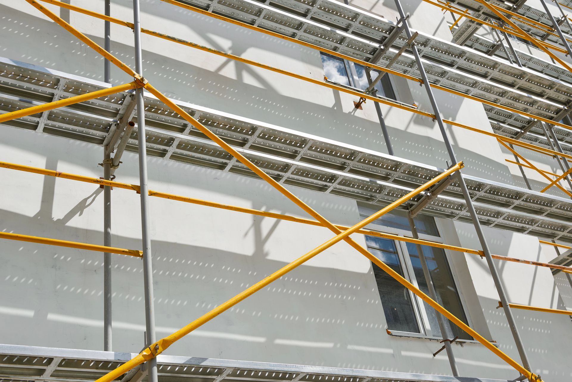 Impalcature gialle sulla facciata bianca dell'edificio.