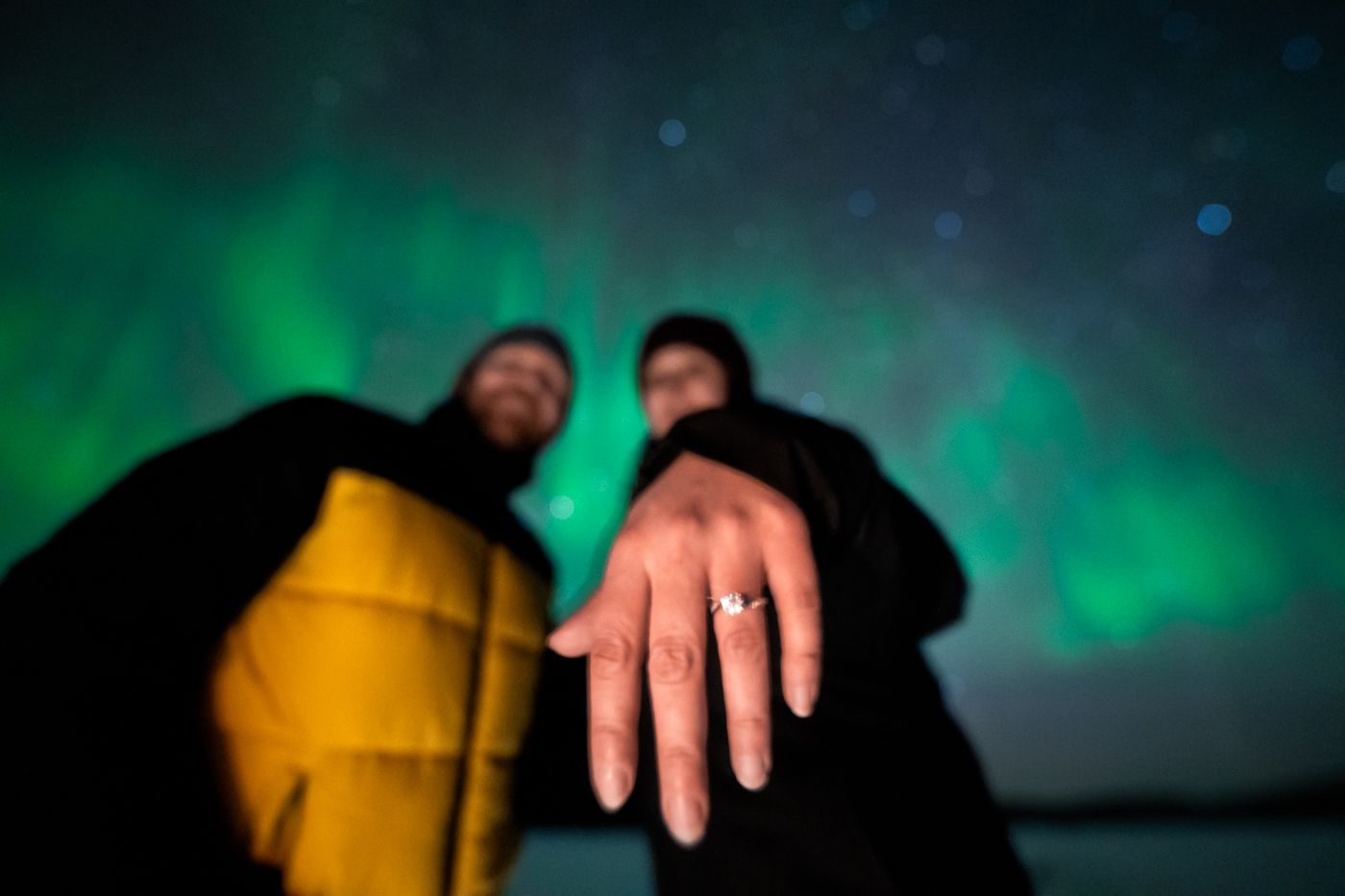 Guest showing engagement ring under Aurora after proposal on Arctic GM tour in Tromsø