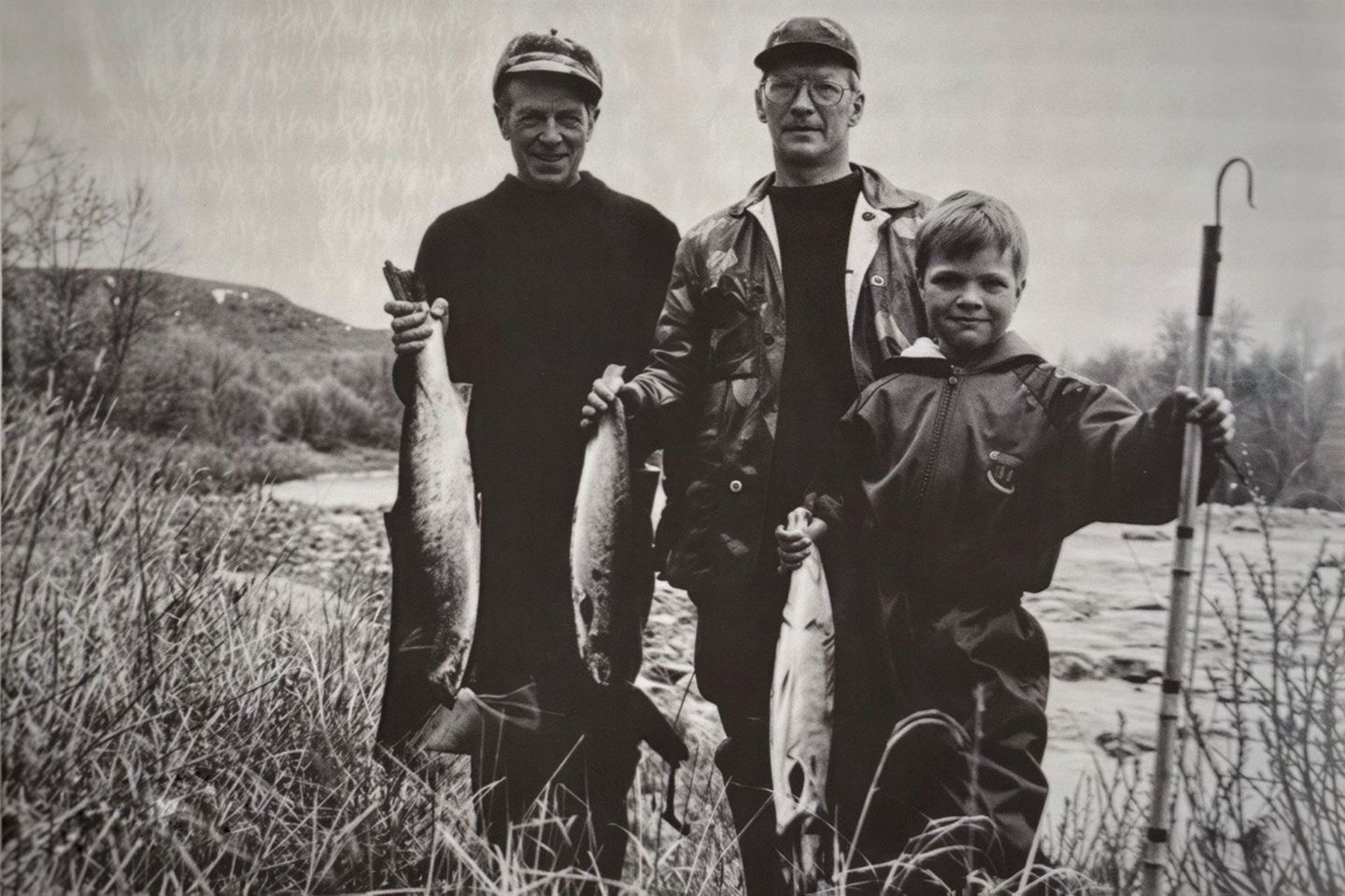 Arctic GM family members holding freshly caught fish beside a river in Lapland
