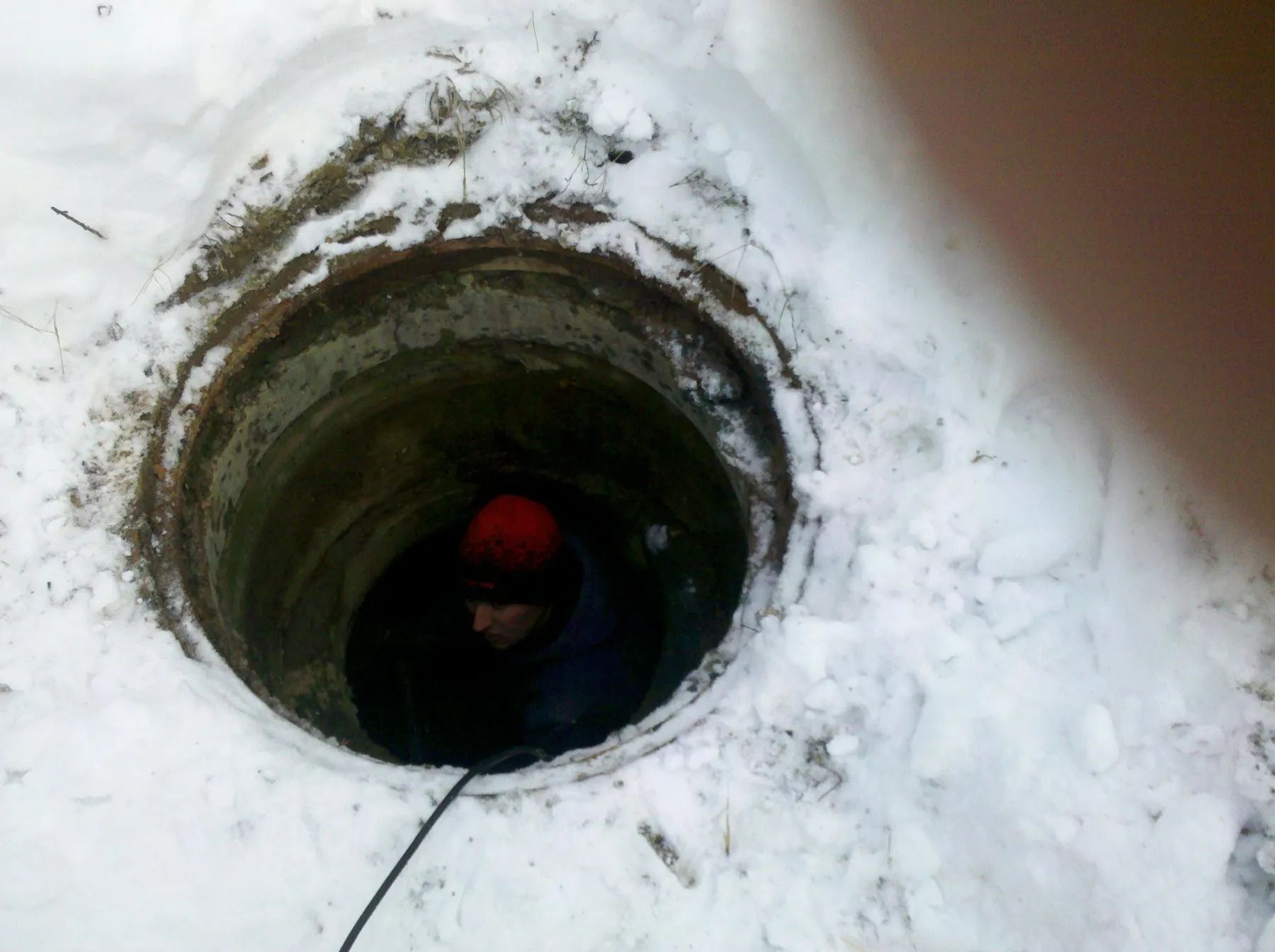 A man is looking out of a hole in the snow.