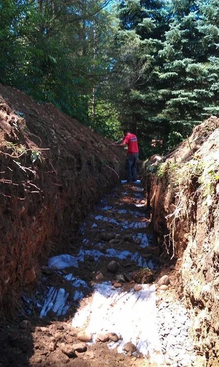A man in a red shirt is digging a hole in the ground.