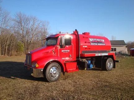 A red truck is parked in a grassy field.