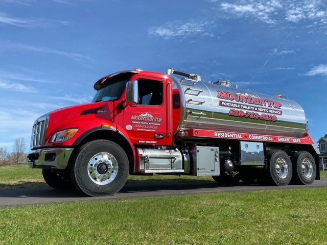 A red and silver truck is parked in a grassy field.