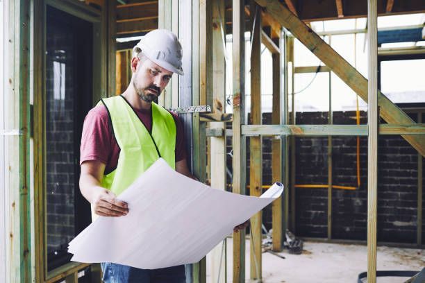 A construction worker is looking at a blueprint at a construction site.