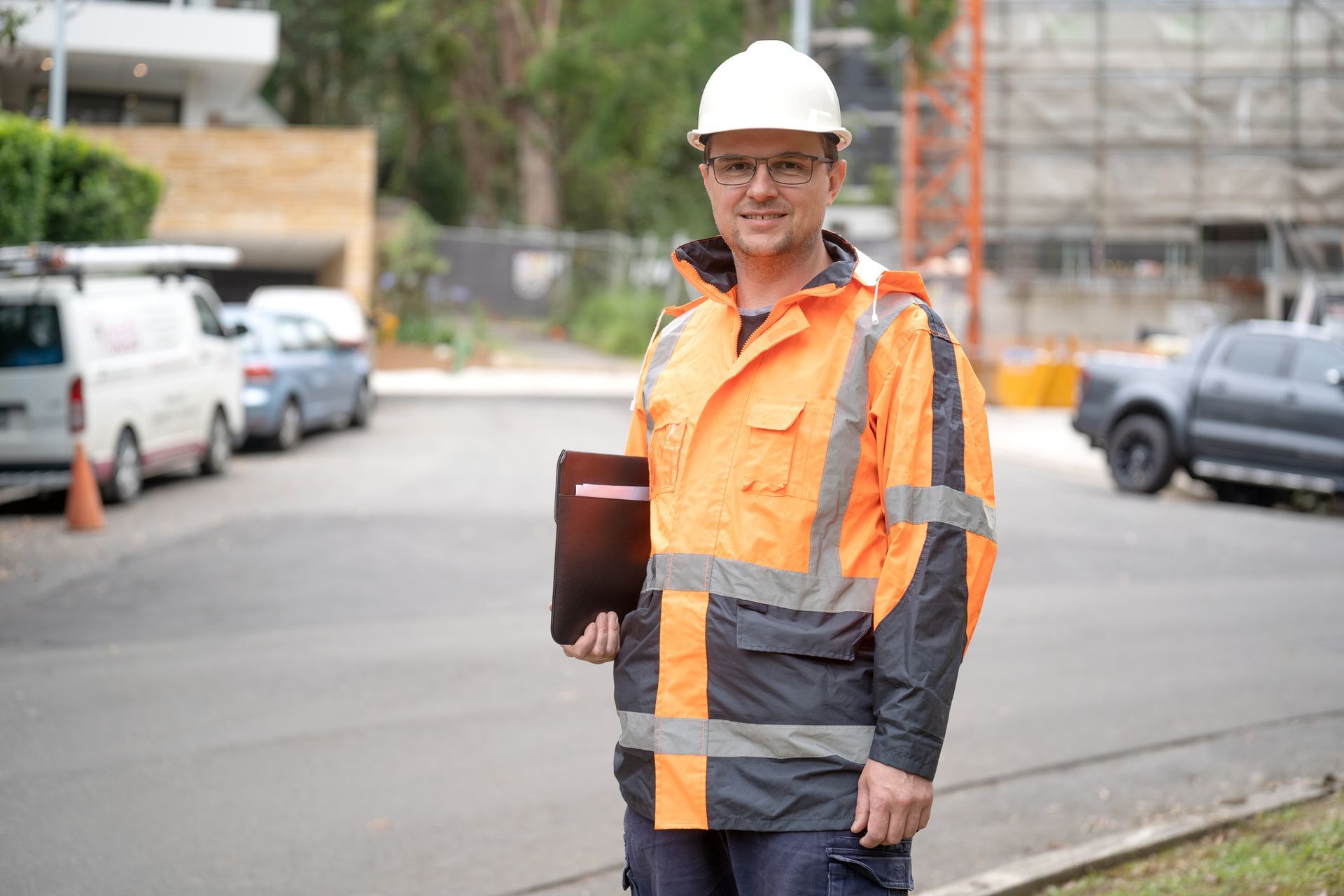 A construction worker is standing on the side of the road holding a clipboard.