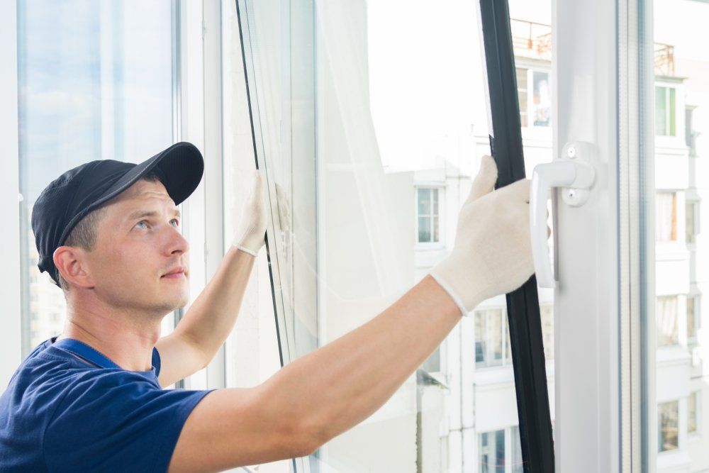 A Man Is Installing A Window In A House — Canberra Handyman Solutions In Wanniassa, ACT