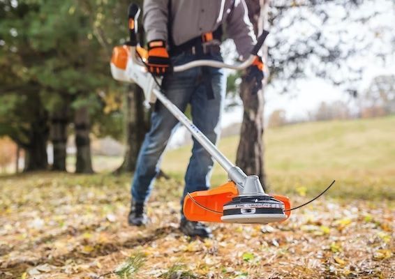 A Man Is Using a Lawn Mower in A Park — Stihl Shop Grafton in Yamba, NSW