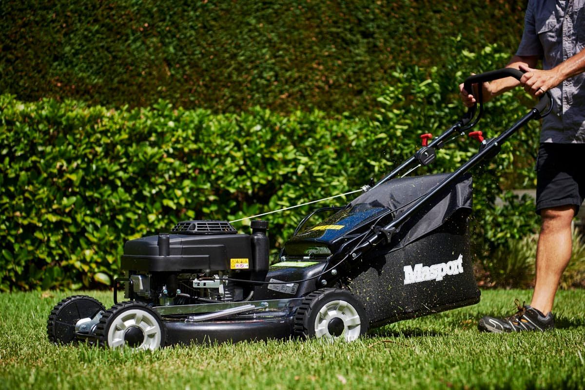 A Man Is Using a Lawn Mower to Cut the Grass — Stihl Shop Grafton in Clarence Valley, NSW