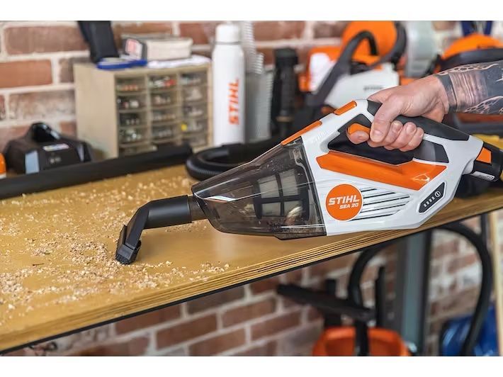 A Person Is Using a Handheld Vacuum Cleaner on A Wooden Table — Stihl Shop Grafton in Grafton, NSW