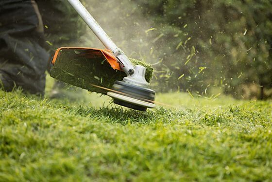 A Person Is Using a Lawn Mower to Cut the Grass — Stihl Shop Grafton in Clarence Valley, NSW
