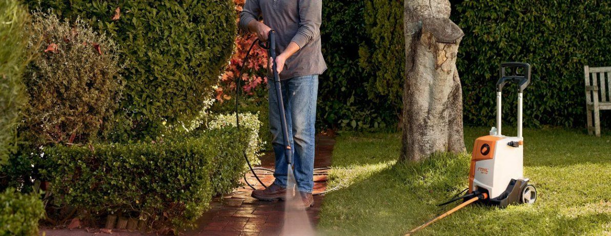 A Man Is Using a High Pressure Washer to Clean a Lawn — Stihl Shop Grafton in Grafton, NSW