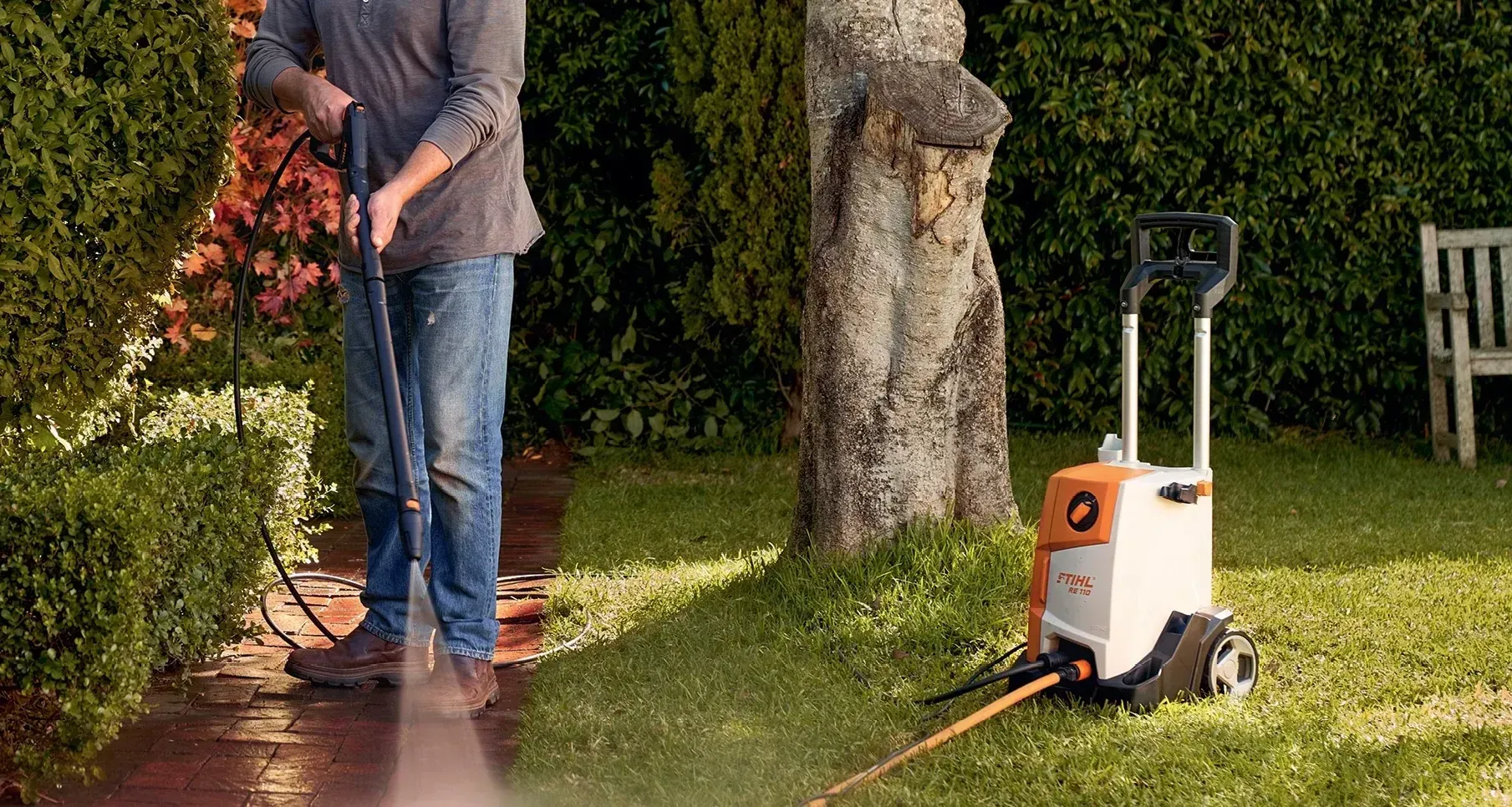 A Man Is Using a High Pressure Washer to Clean a Sidewalk — Stihl Shop Grafton in Yamba, NSW