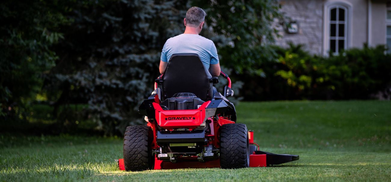 A Man Is Riding a Lawn Mower on A Lush Green Lawn — Stihl Shop Grafton in Clarence Valley, NSW