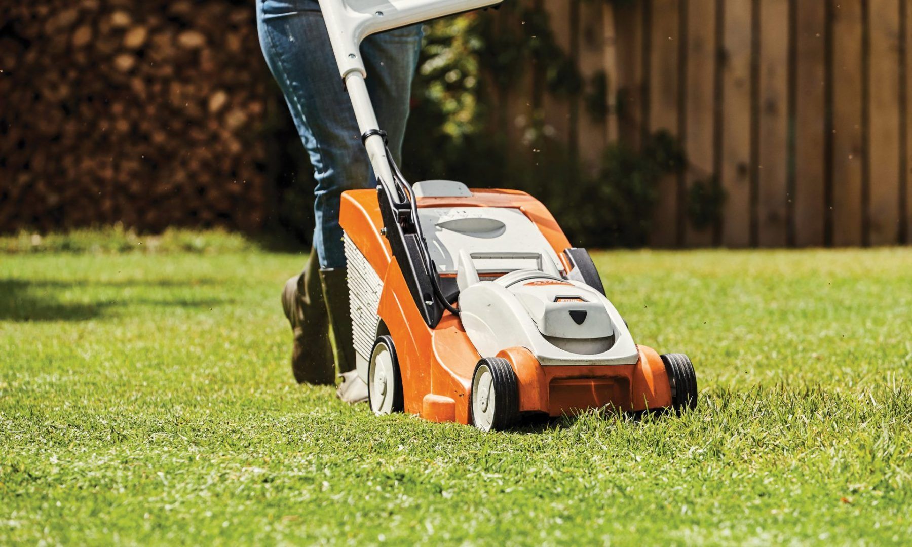 A Person Is Mowing a Lush Green Lawn with A Lawn Mower — Stihl Shop Grafton in Grafton, NSW