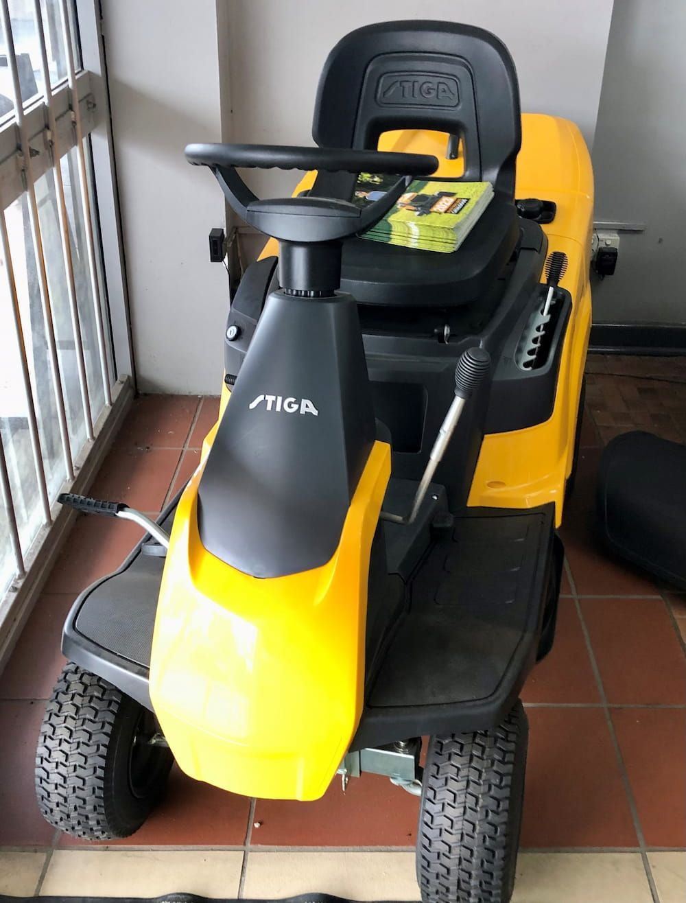 A Yellow and Black Lawn Mower Is Parked in Front of A Window — Stihl Shop Grafton in Grafton, NSW