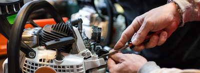 A Man Is Fixing a Chainsaw with A Wrench — Stihl Shop Grafton in Grafton, NSW
